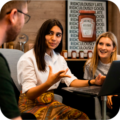 A group of people sitting around a table with a laptop.