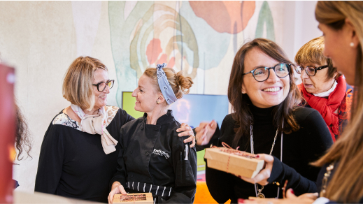 Two women smiling at one another with one woman wrapping her arm around the other.