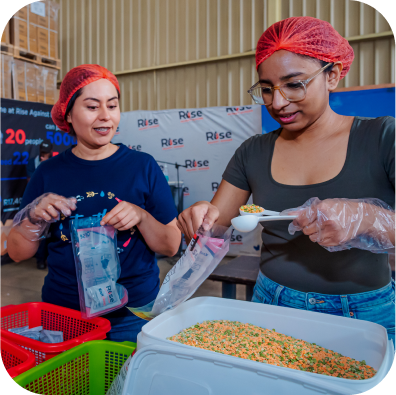 Two women are preparing food in a warehouse.
