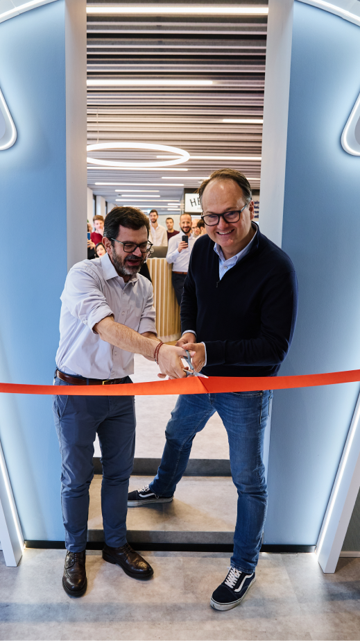 2 men smiling and cutting an opening ribbon
