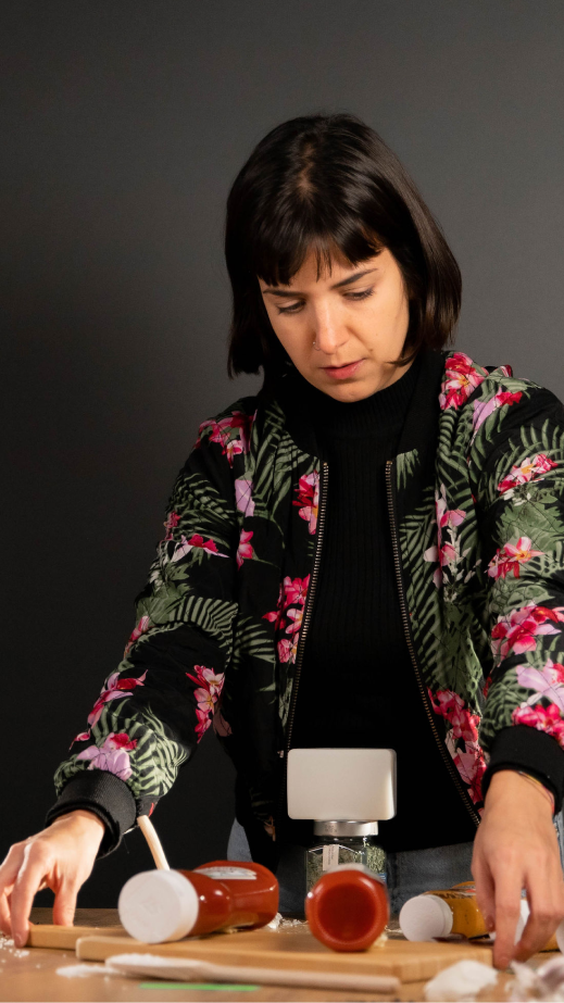 A woman preparing food and bottles of sauce on a table