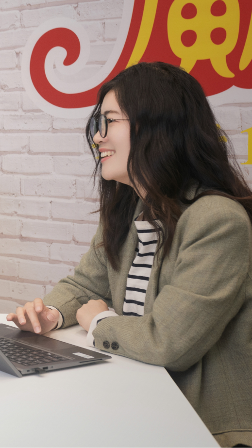 a woman smiling whilst working on a laptop