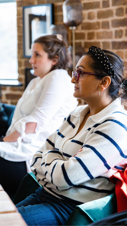 A woman sitting at a table with her arms crossed and focusing.