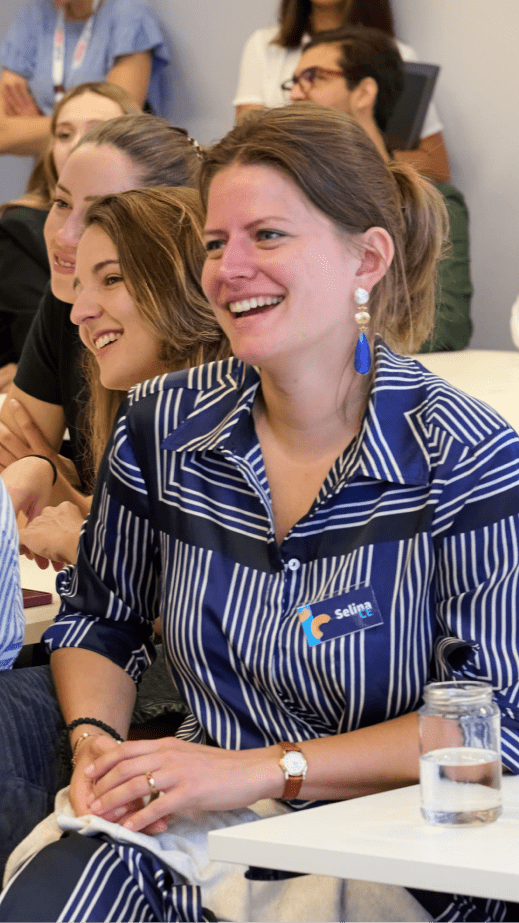 A woman in a blue and white striped dress smiling, looking to the left.